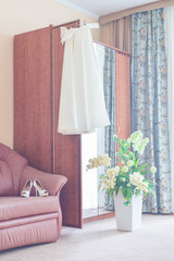 Vertical photography. Preparations for the wedding. Morning bride. The dress hangs on the wardrobe, shoes are on the couch in a beautiful room