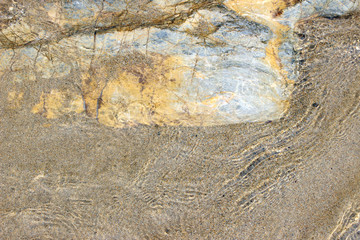 Beach sand and rock close up with transparent wave surface texture horizontal