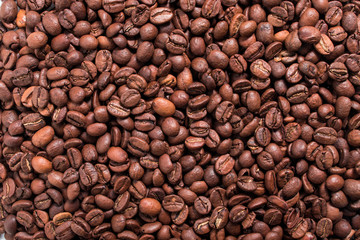 Arabica roasted coffee beans scattered close-up, texture of fragrant coffee beans