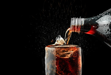 Pour soft drink in glass with ice splash on dark background.