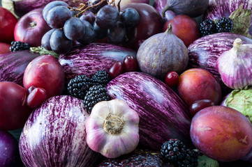 Background of fresh vegetables and fruits. Purple eggplant, backberries, grapes, plums, figs,...