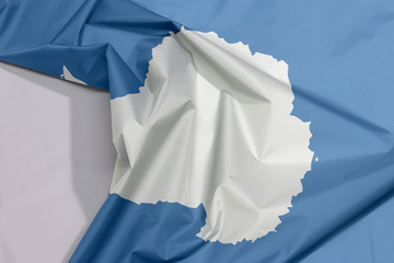 Antarctica fabric flag crepe and crease with white space, A plain white map of the continent on a blue background.