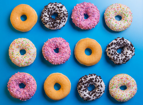 Top view of many colorful donuts on blue background.