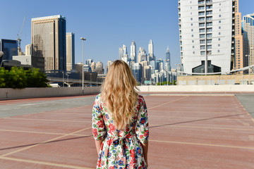 Fototapeta na wymiar Young woman in floral colorful dress and with light hair in Dubai city