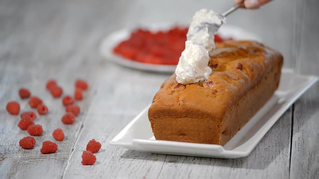 Making cake with cream and raspberries