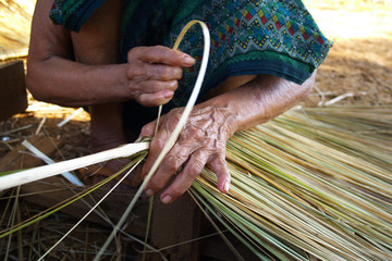 Hand of old woman weaving wicker 