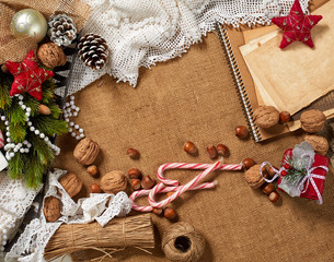 Fototapeta na wymiar Christmas decoration background, fir tree, textile, beads, gifts, old paper, nuts and other stuff on sackcloth. Empty space for text, new year theme.