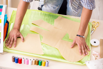 Young handsome tailor working in his workshop
