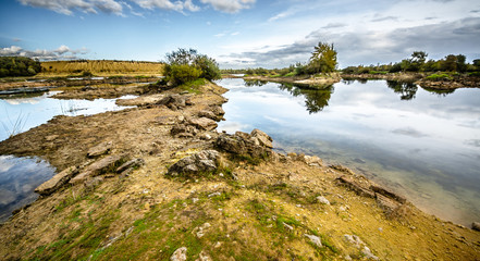 Sandy hills. Lake in the Sandy canyon. Warm colors background. Yellow sandstone textured mountain, white thin sand dune, bright sky. Sunshine landscape