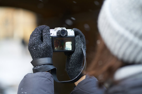 girl in gloves in the fall photographs professional camera. view from over the shoulder, the camera in hand.