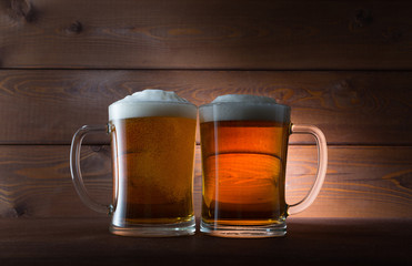 Two glasses of golden beer on wooden background