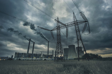 Power plant "Pocerady" with high voltage power line, pylon, chimneys and cooling towers with dramatic clouds in the evening