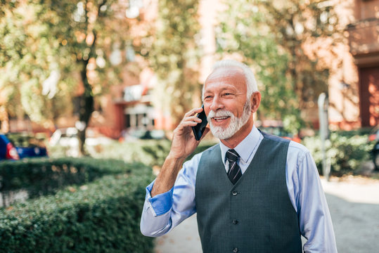 Charming Older Business Man Talking On The Phone Outdoors.