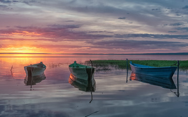 sunset rays reflected from wooden boats in the calm water of a lake Plesheevo in Pereslavl Zalessky