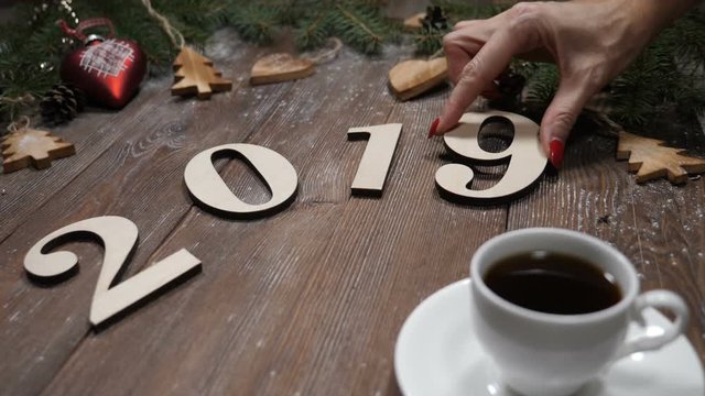 Merry Christmas and happy new year concept. Ney year symbols put on wooden background together with a cup of coffee. Female hand puts numerical symbols 2019. Video postcard. hd