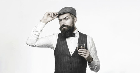 Degustation, tasting. Man with beard holds glass of brandy. Bearded man wearing suit and drinking whiskey, brandy, cognac. Bearded and glass of whiskey. Sommelier tastes expensive drink.