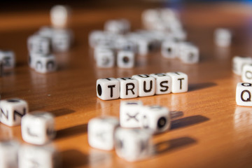 The word TRUST made of white plastic blocks on the table. Letter concept.