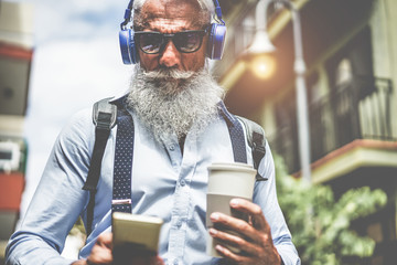 Happy senior man listening music playlist app and drinking coffee at early morning time