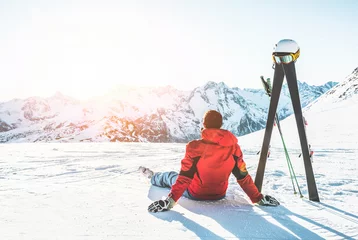 Abwaschbare Fototapete Wintersport Skifahrer, der an einem sonnigen Tag in den Alpen sitzt - Erwachsener Mann, der den Sonnenuntergang mit Skiausrüstung neben ihm genießt - Wintersport- und Urlaubskonzept