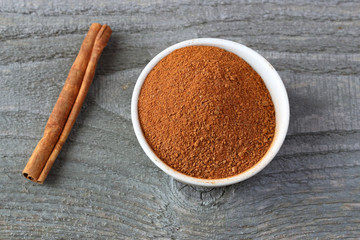 Cinnamon powder and stick on wooden background