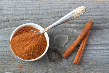 Cinnamon powder and sticks on wooden background