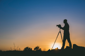 Silhouette of black photographer at sunset