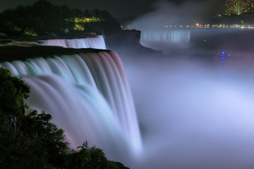 Niagara Falls lit at night by colorful lights. Niagara Falls, NY, USA.