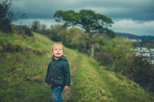 Little toddler walking on hillside in autumn