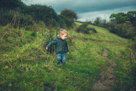 Little toddler walking on hillside in autumn