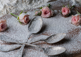 still life flowers with flour and spoons and a brush. presented on a wooden basis