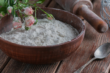 still life flowers with flour and spoons and a brush. presented on a wooden basis