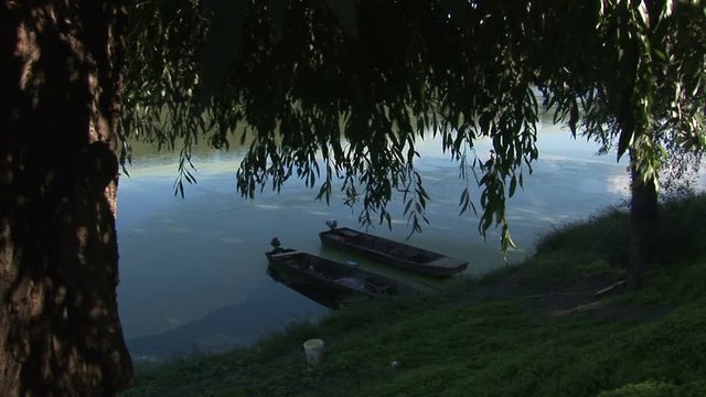 Two fishing boats on the river near willow tree