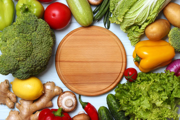 Fresh vegetables and wooden board for cutting on a wooden table. Top view. Healthy food, dishes and vegetables, diet, vegetarianism