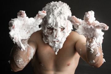 photo portrait of a muscular man smeared with shaving foam with hands exposed in front of him frightening