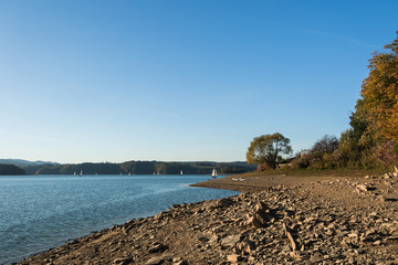 Autumn. Stone beach. Sailboats sailing on the lake.