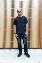 Close up of attractive dark-skinned man in black T-shirt on wooden background.