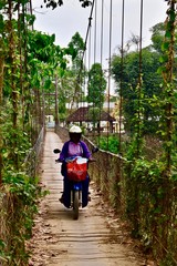 Lady on a bike crossing a very old bridge in Battambang, Cambodia.