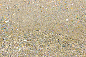 Beach sand with transparent wave close up surface texture horizontal 