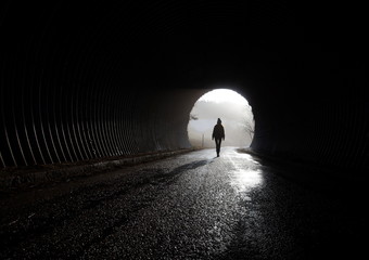 Licht am Ende vom Tunnel, Silhouette geht durch die Dunkelheit