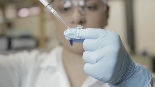 A handheld shot of a researcher transfering samples to smaller vials in a genetic laboratory at university 