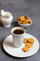 Cup of coffee with sweet mini cookies  on grey concrete background. Free space for text.