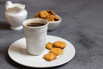 Cup of coffee with sweet mini cookies  on grey concrete background. Free space for text.