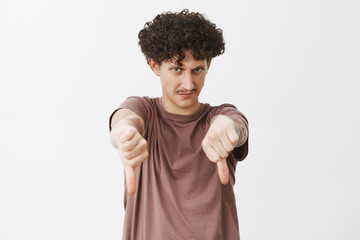 Funny displeased and unimpressed jewish guy with curly hair and moustache looking from under...