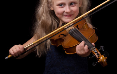 Blonde little girl learning to play the violin isolated on black © laboko