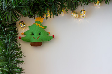 Christmas Frame Decorations Cute and cuddly felt christmas tree, Lights, .Green tinsel . White background. Copy Space . Top view