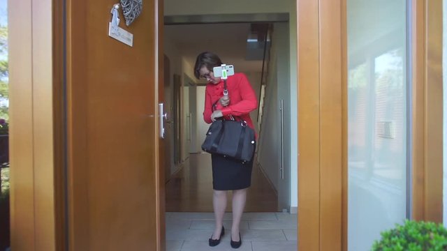 woman opens handbag at the door of a house