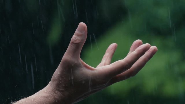 Slow motion 180fps closeup: Man uncurls fist into open palm in pouring rain