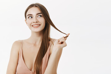 Flirty woman having naughty thoughts in mind rolling lock of hair on finger and smiling curiously...