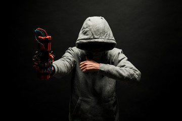 The silhouette of a man in the hood on a black background, his face is not visible, shows hands...