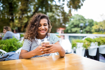 Beautiful l latin girl successful freelancer writes a text message on your phone while sitting in...